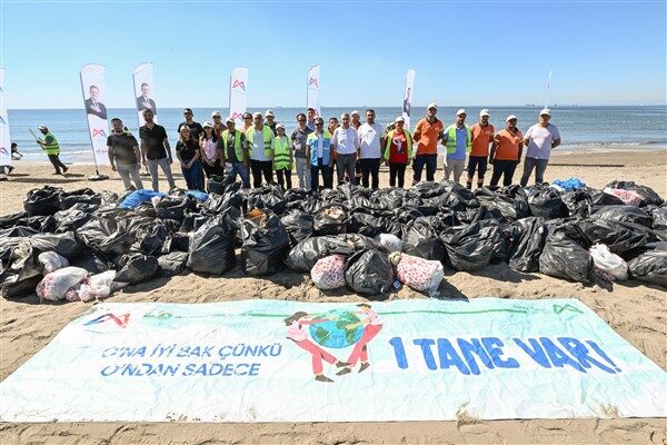 Ellerine eldivenlerini takan katılımcılar, sahilde biriken plastik atıklardan cam şişelere,