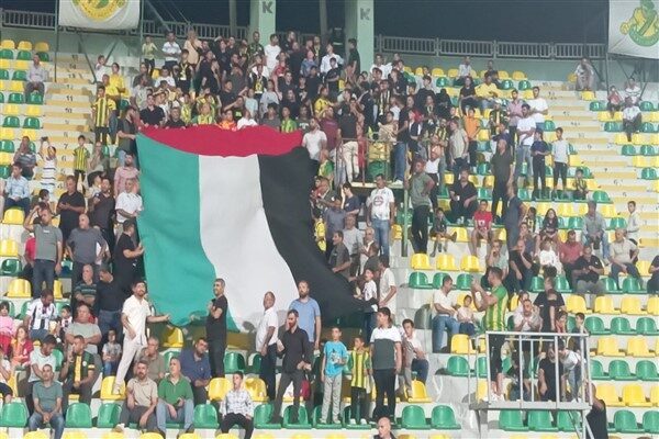 Sarı yeşilli taraftarlar, tribünlerde açtıkları Filistin bayrağı ile “Kahrolsun İsrail”